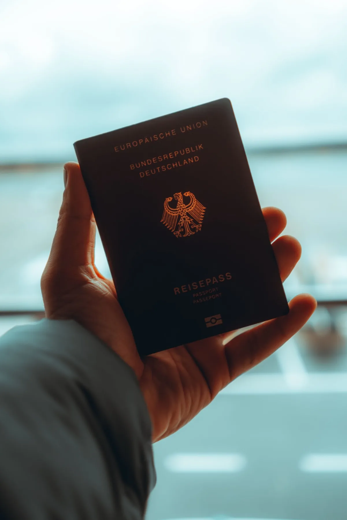 Travel document held near a window as an illustrative document-preparation visual