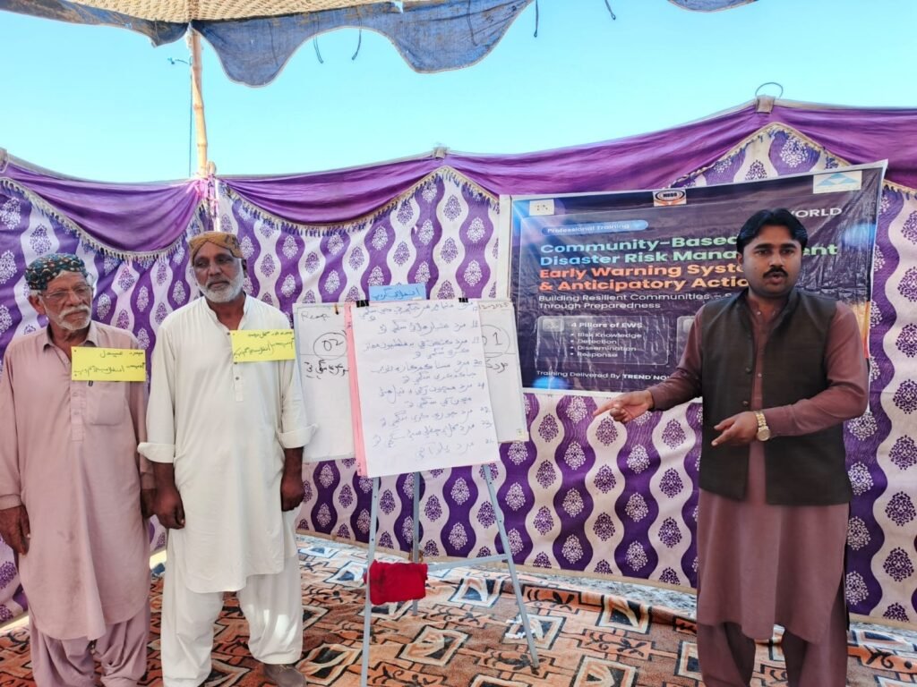Trend Nova World Development Sector team conducting an early warning and anticipatory action awareness session with community members, engaging participants in discussions on disaster risk preparedness, early warning systems, and proactive response measures in a local community setting.